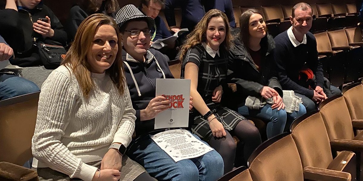 Attendees enjoying a relaxed performance, seated in an auditorium, creating a welcoming and inclusive atmosphere.