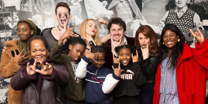 A group of individuals smiling and posing together, capturing a moment of camaraderie during a relaxed performance event.