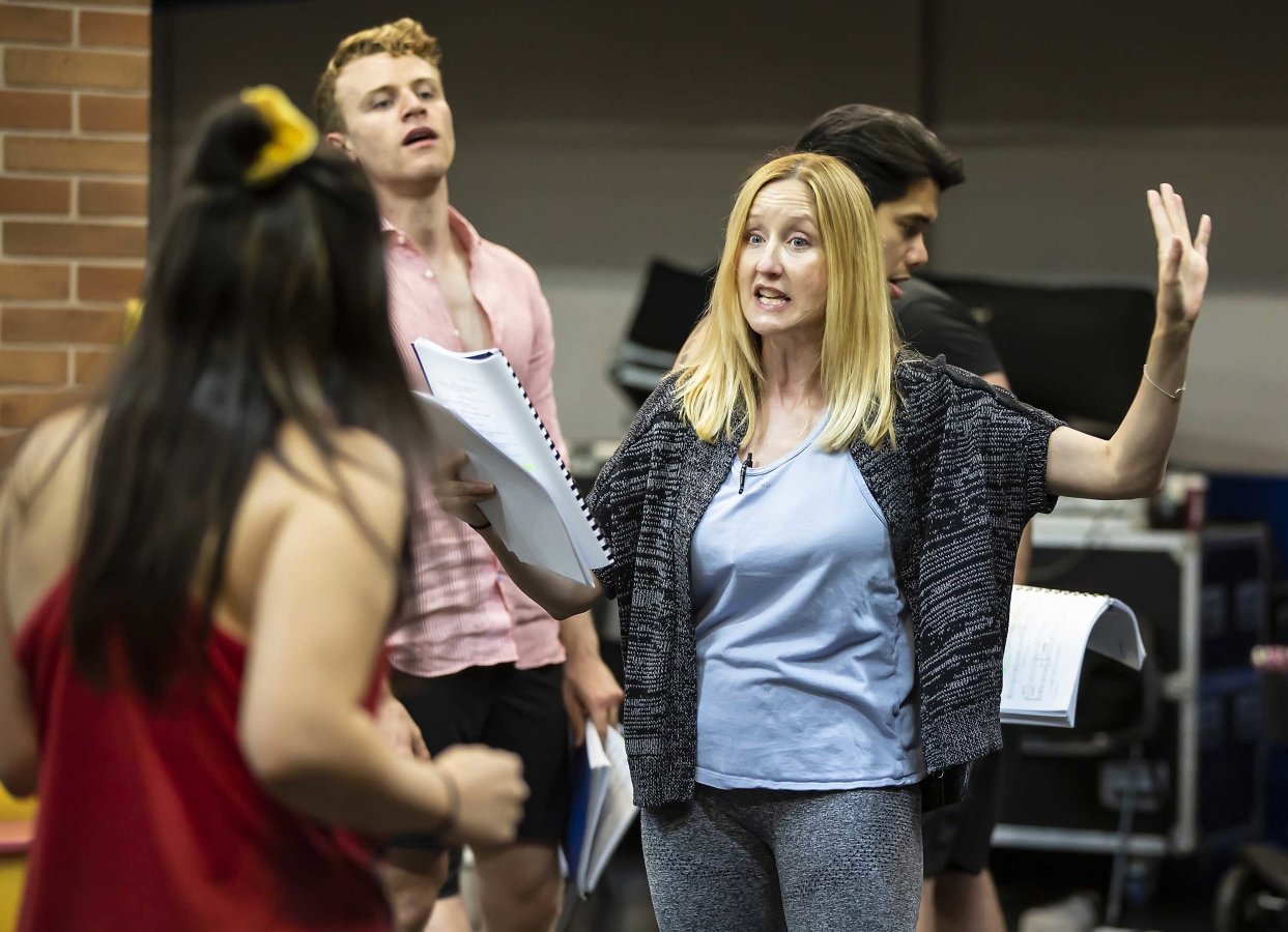 Lauren Ward stands talking to another member of the cast