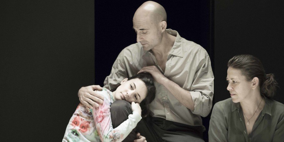 Phoebe Fox is being held by Mark Strong with Nicola Walker sat next to them.