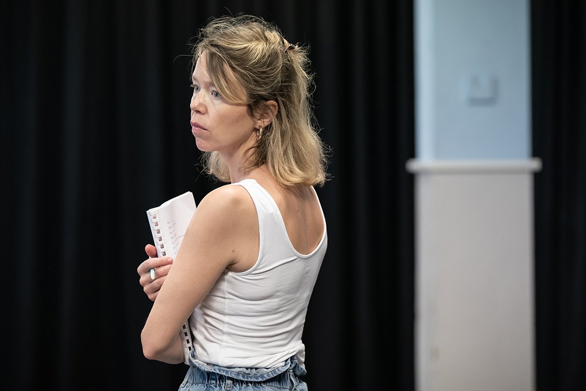 Anna Maxwell Martin stands holding a script, looking over her shoulder.