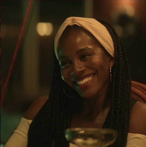 Deborah Ayorinde in Them, an Amazon Original TV series. Deborah wears a pale headband, hoop earrings, black braids and a pale off-the-shoulder top.