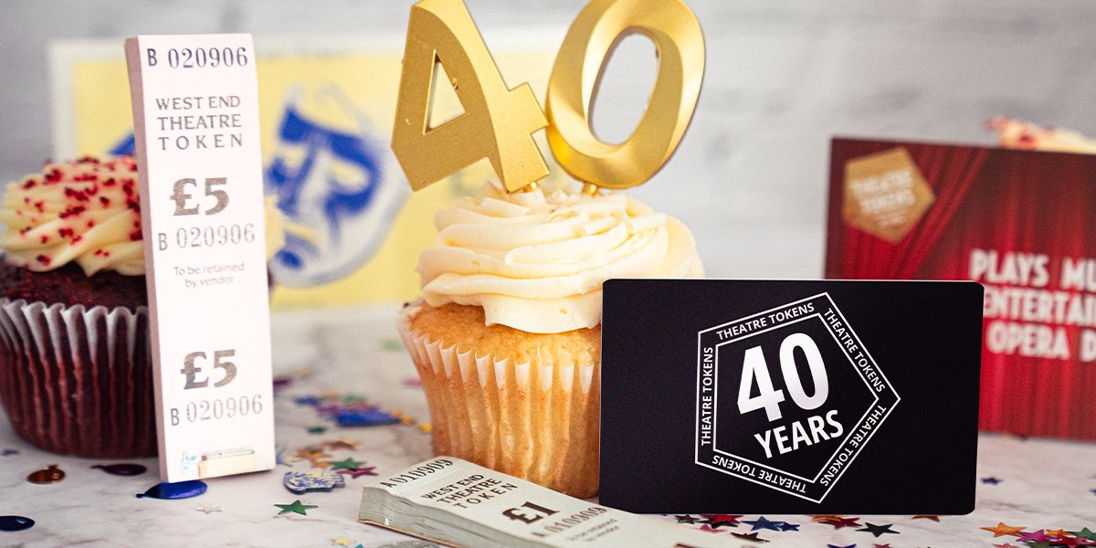A cupcake with candles with the numbers 4 and 0 is surrounded by multicoloured confetti and a variety of Theatre Tokens vouchers, including 'West End Theatre Token' paper tickets from 40 years ago, and a black gift card which reads 'Theatre Tokens 40 years'.