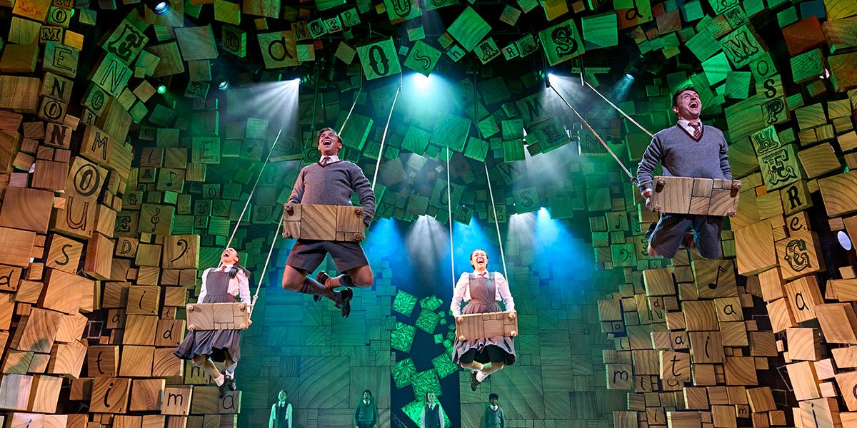 Four schoolchildren laying on swing sets, soaring upwards